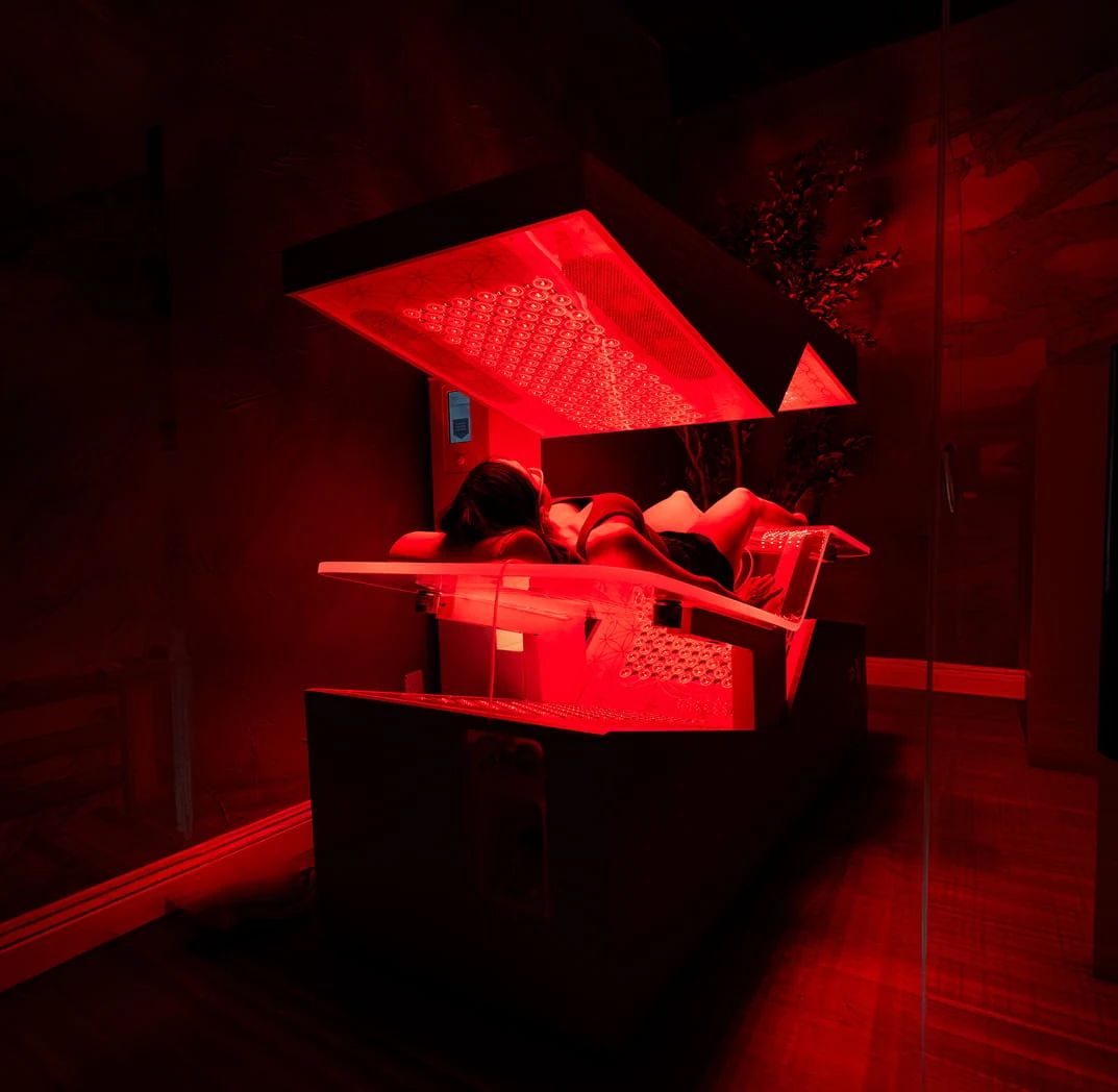 A client lying in the open Ammortal Chamber under its red light array.