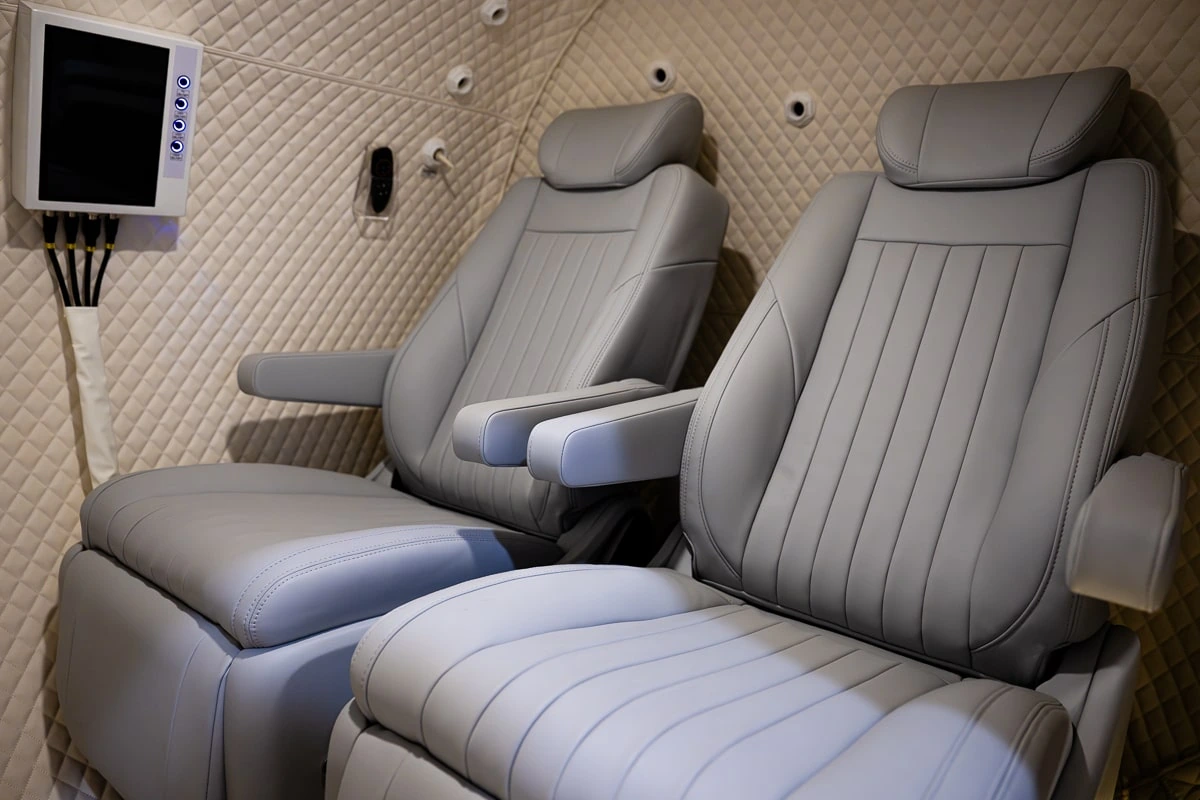 Inside the two-person hyperbaric chamber: two grey leather reclining chairs and a wall-mounted screen.