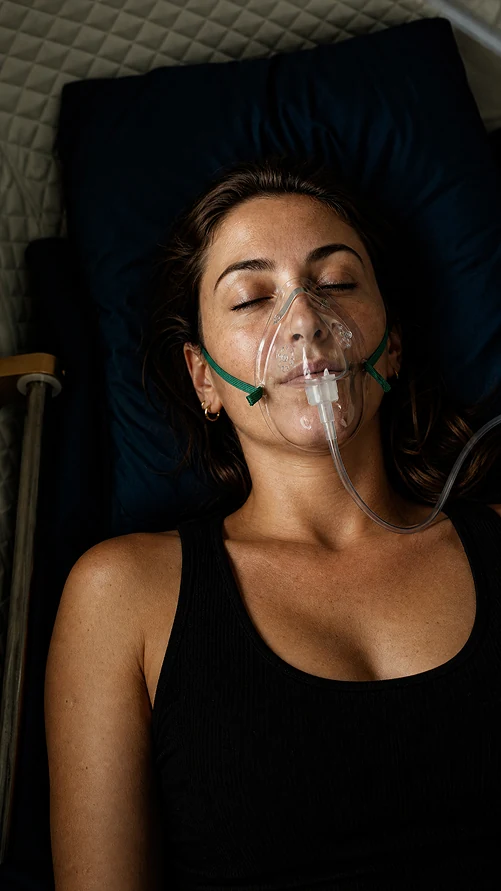 A client lying back with an oxygen mask on, eyes closed, during a session.