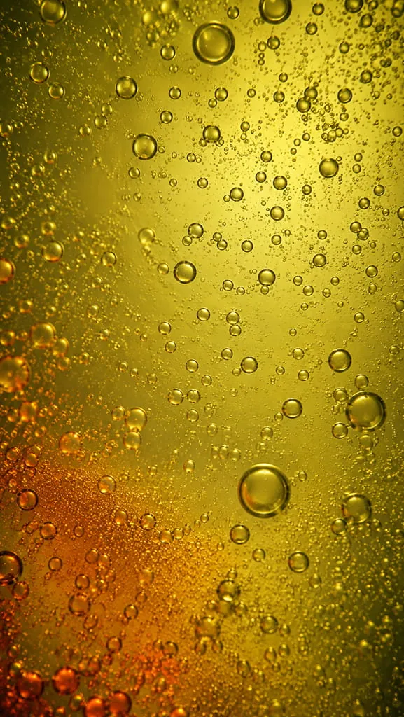 An abstract macro of golden bubbles rising through fluid.