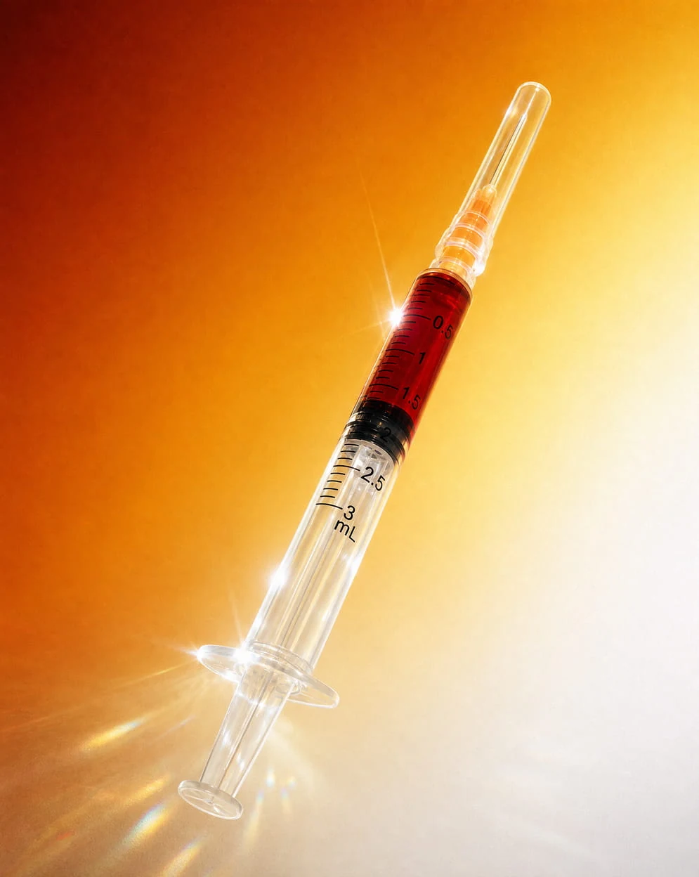 A syringe part filled with red fluid, lit against a warm amber ground.