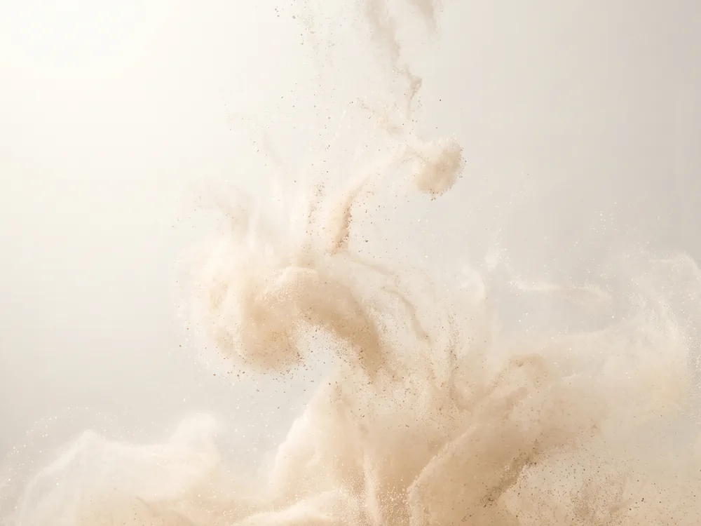 An abstract macro study of fine sand coloured sediment drifting through water.