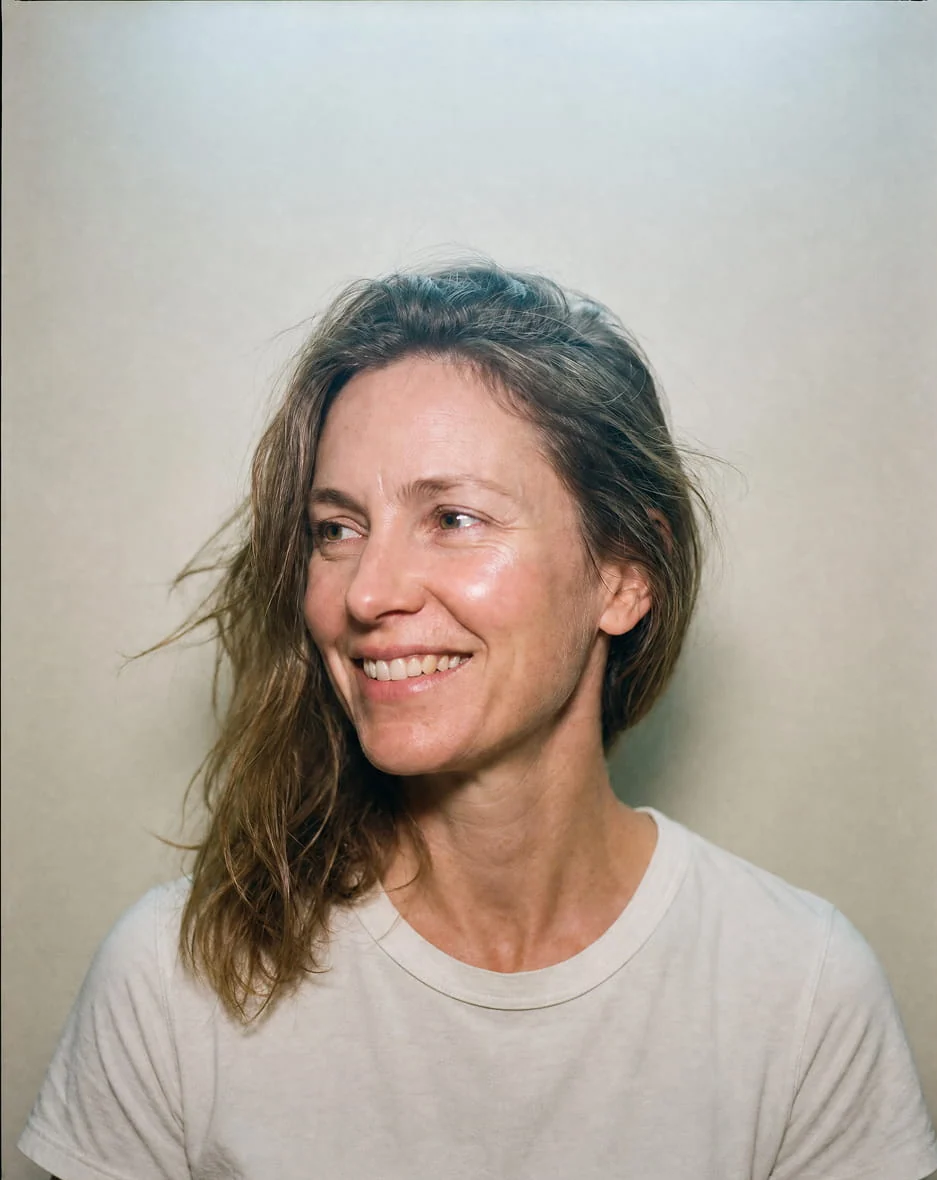 A woman in her forties smiling, unposed, photographed on film.